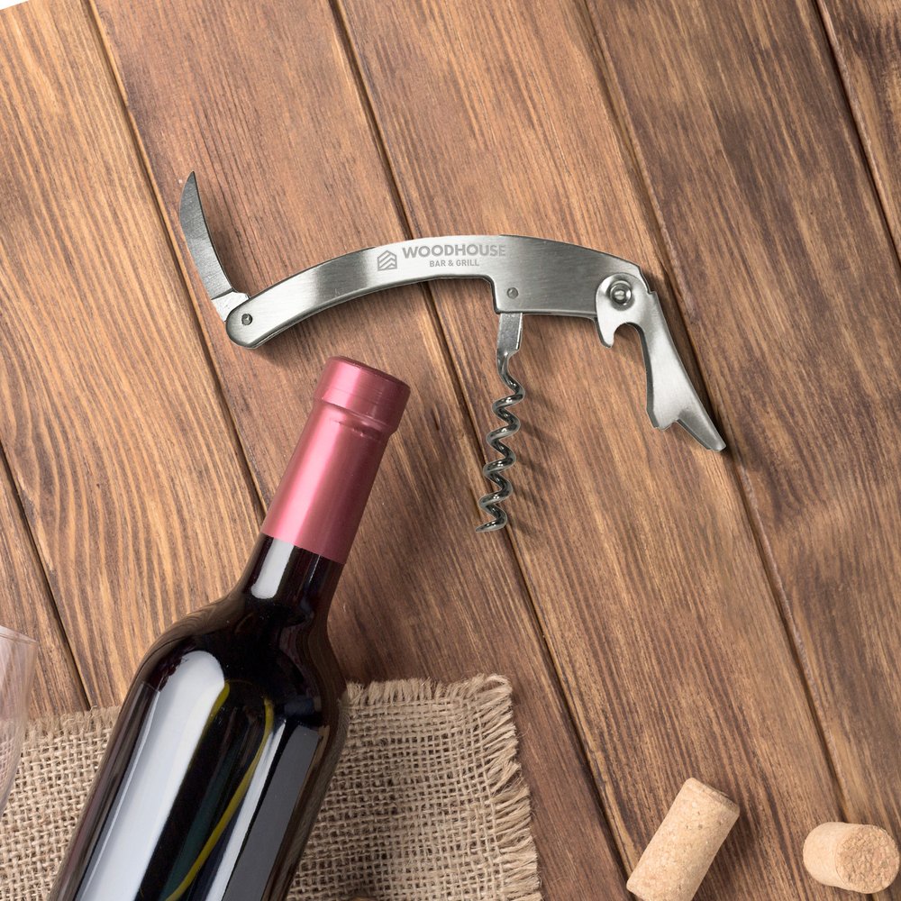 Metal corkscrew beside a wine bottle